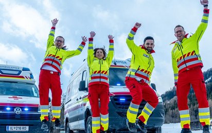 Dein neuer Job im Roten Kreuz Tirol - © Rotes Kreuz Tirol Andreas Amplatz vier Sanitäterinnen springen in Uniform vor einem Auto in die Luft