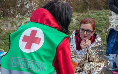 Eine Mitarbeiterin der Krisenintervention im Einsatz - © Rotes Kreuz Schwaz/Andreas Mader Eine Mitarbeiterin der Krisenintervention spricht mit einer Frau, die in einer Rettungsdecke eingewickelt ist. Sie bekommt psychosoziale Unterstützung während einer Krise